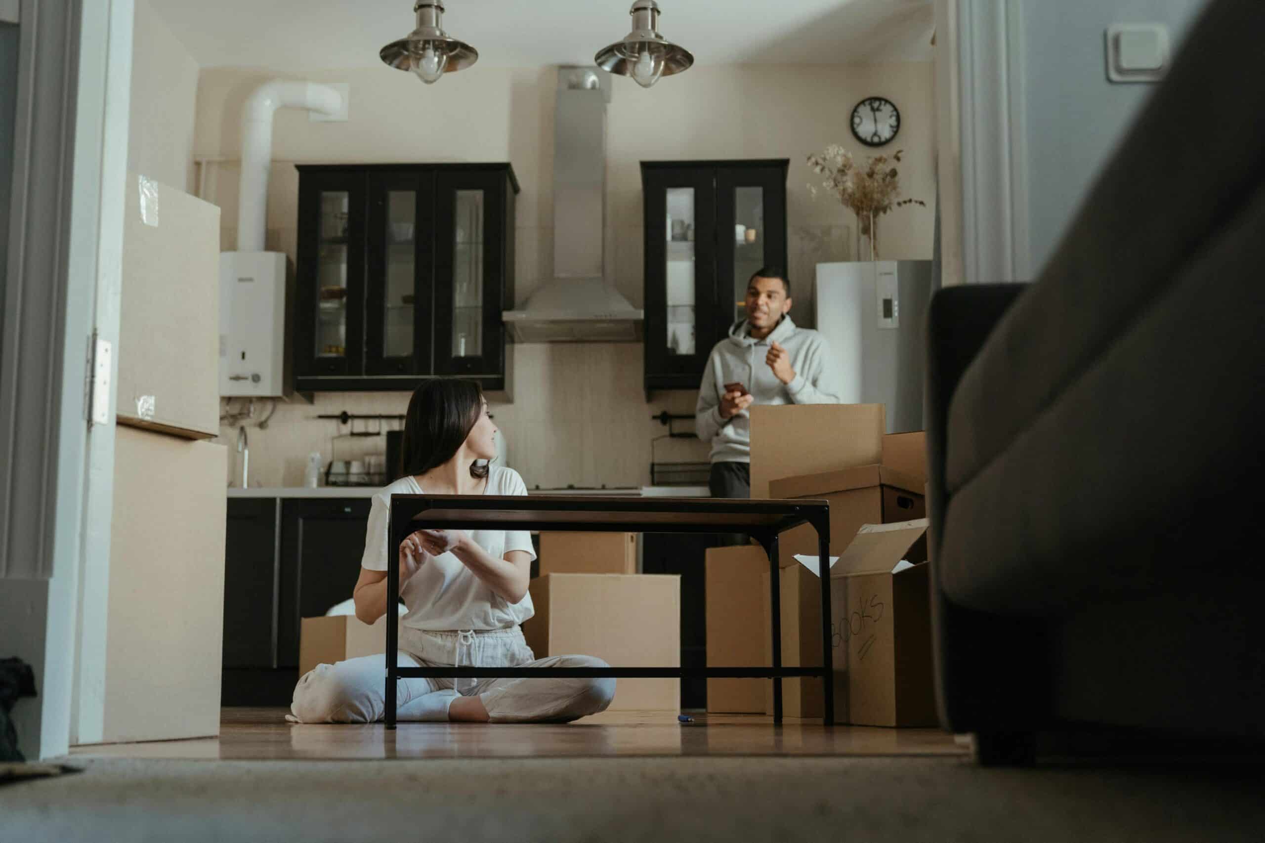 A couple is seen unpacking boxes in their new apartment, setting up their kitchen area.